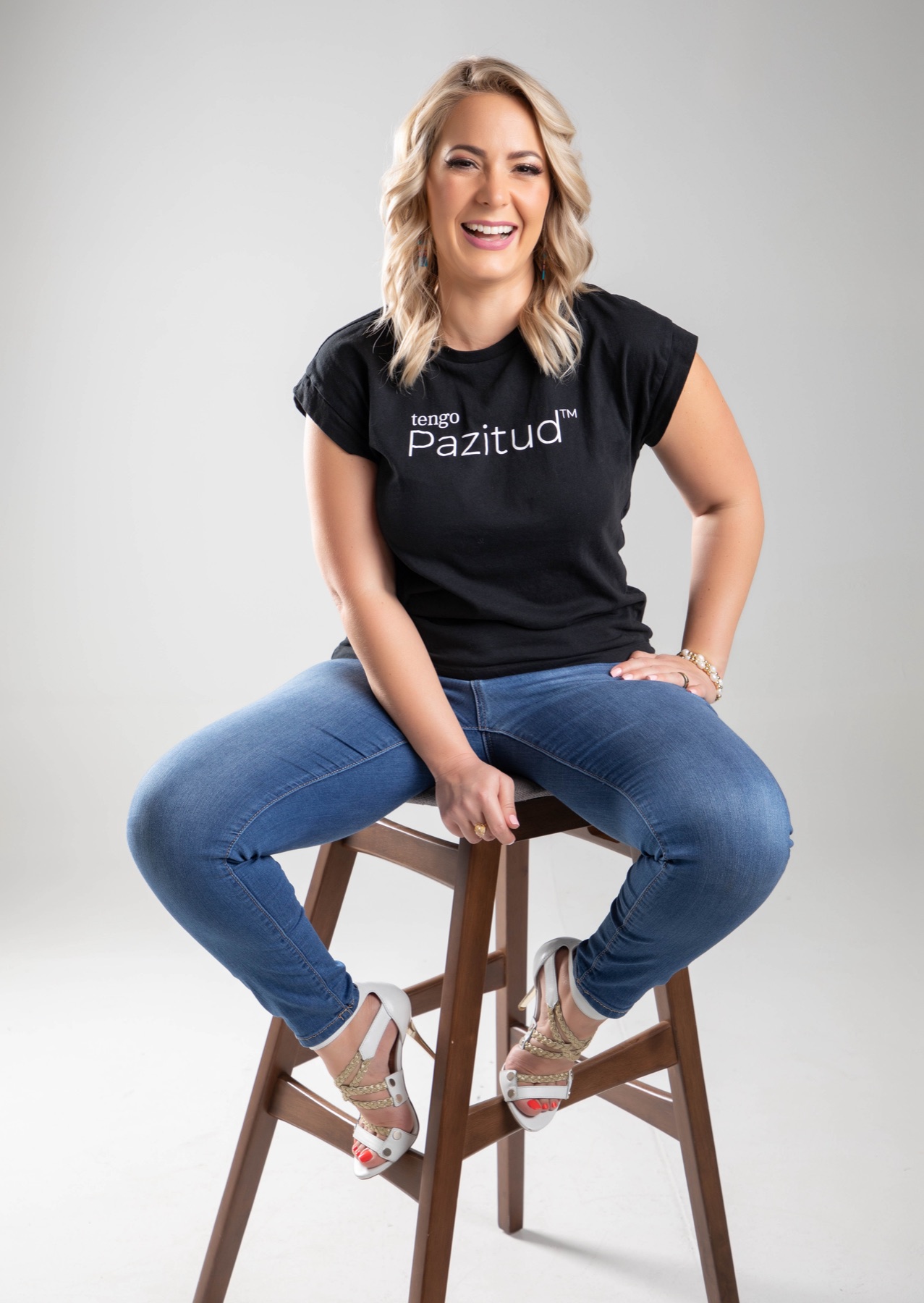 Yane Díaz laughing on a stool in her tengo Pazitud shirt
