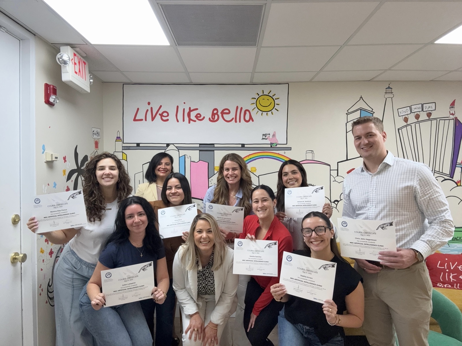 The Live Like Bella nonprofit team holding their AI Clinic certificates at their office